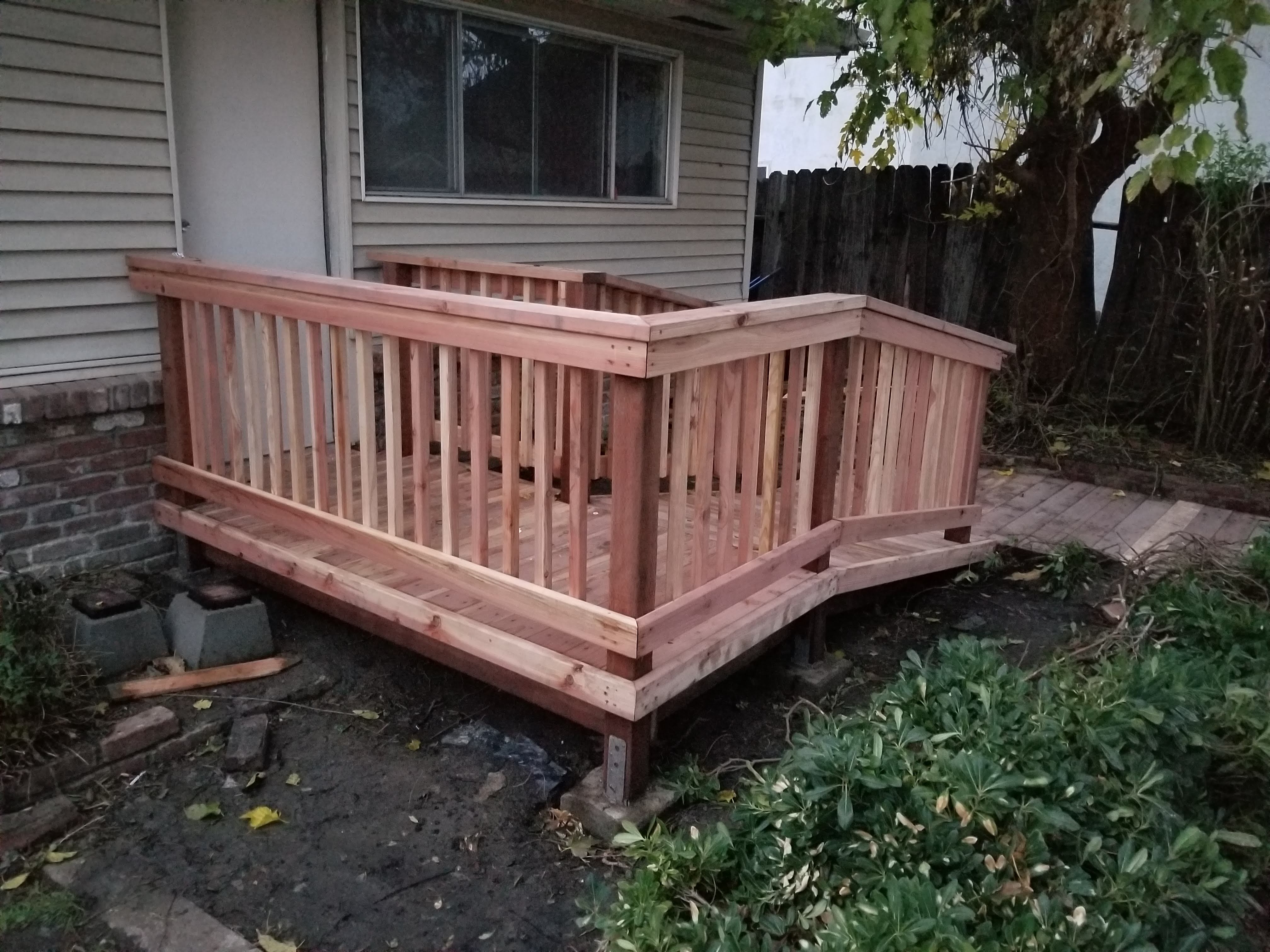 Finished redwood deck with railing at the side of a house