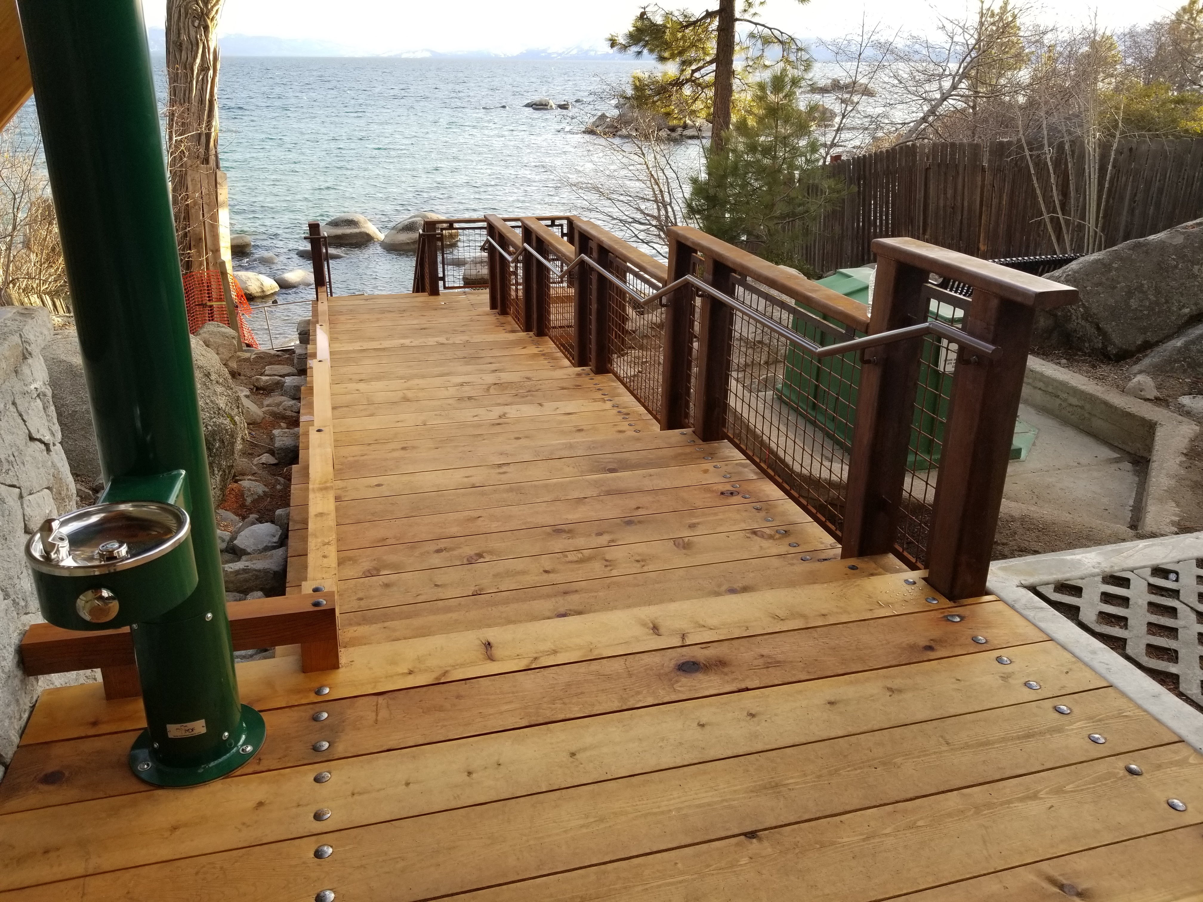 Cedar boardwalk with guardrail leading toward a lake