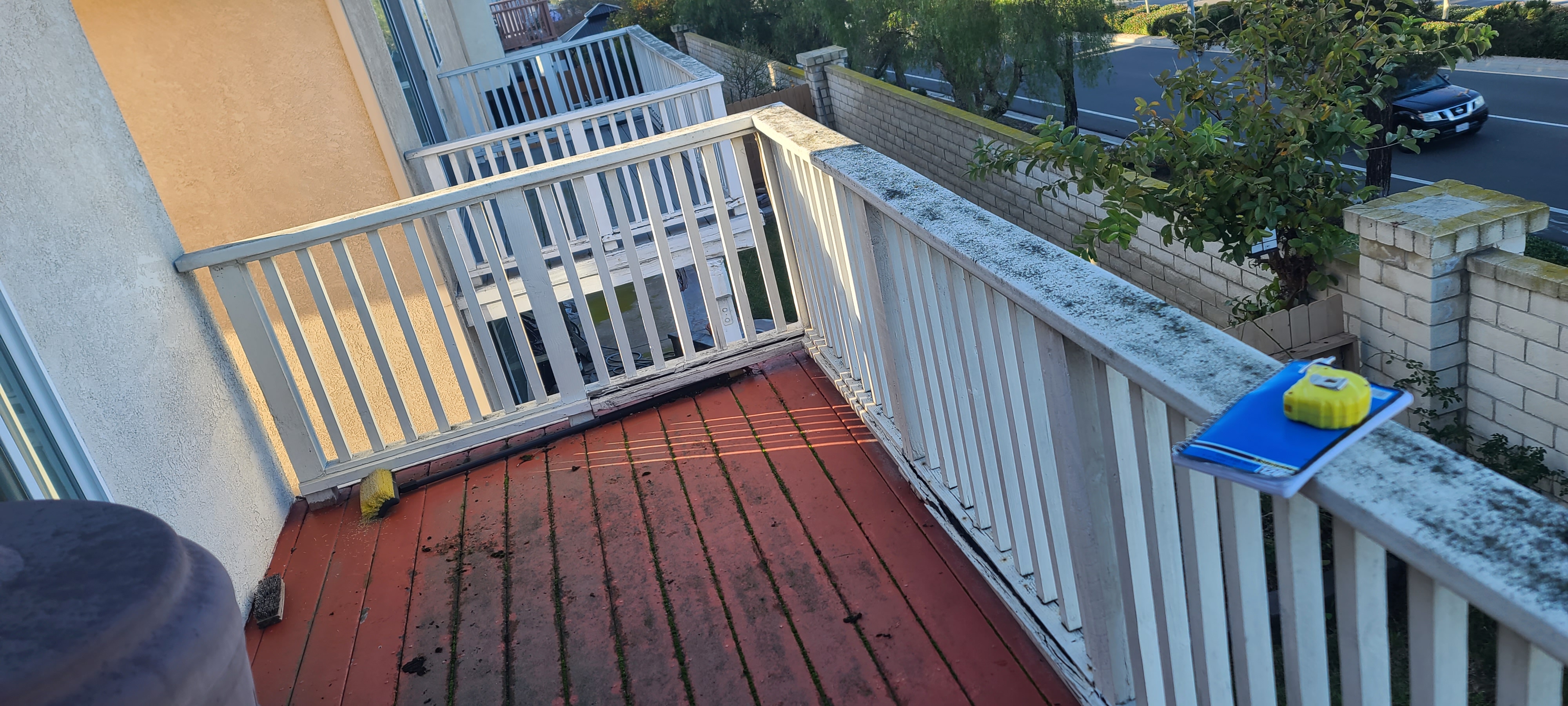 Apartment balcony with white wood railing and red deck surface