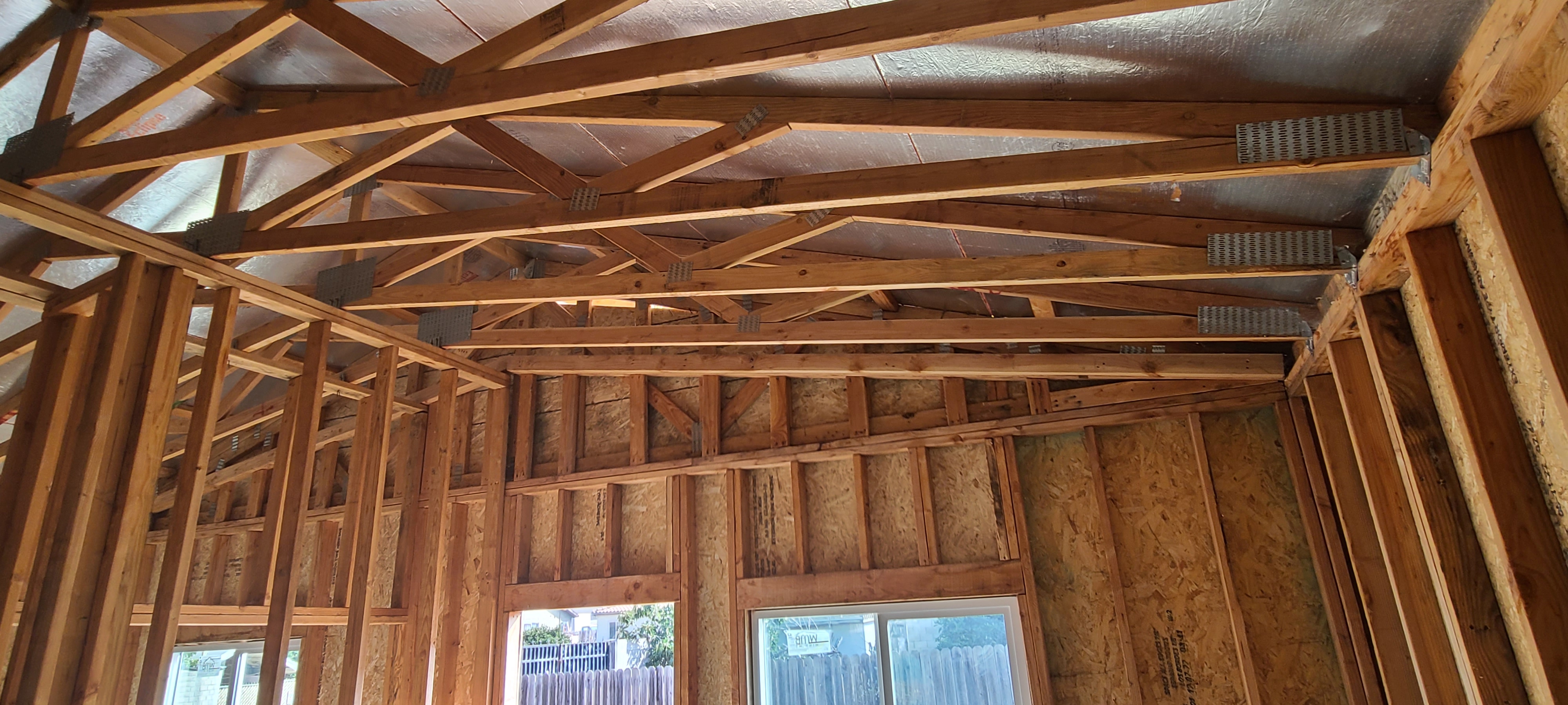 Interior of a new wood-framed structure with roof trusses and windows