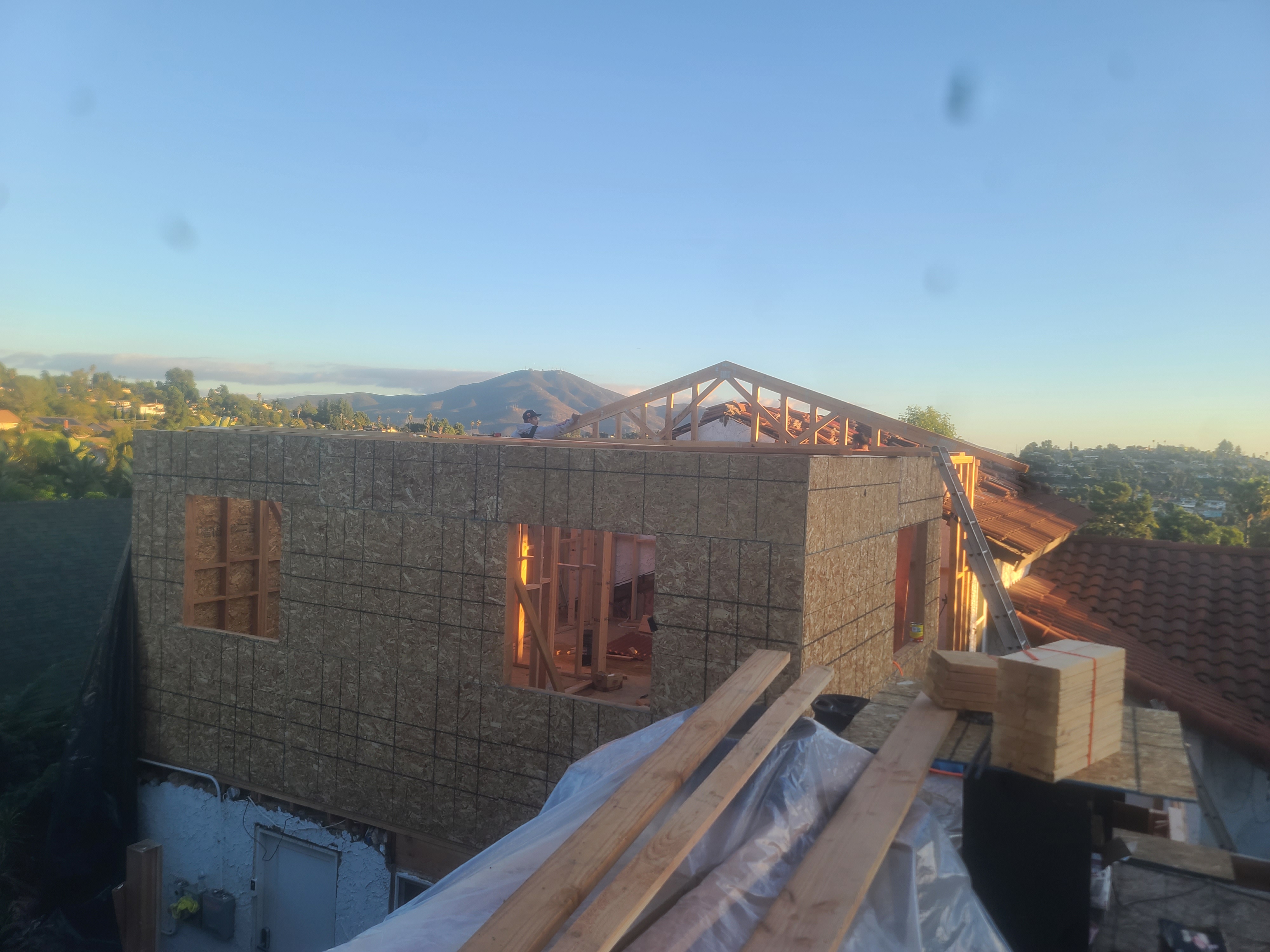 Second-story addition framing with roof trusses on a hillside house